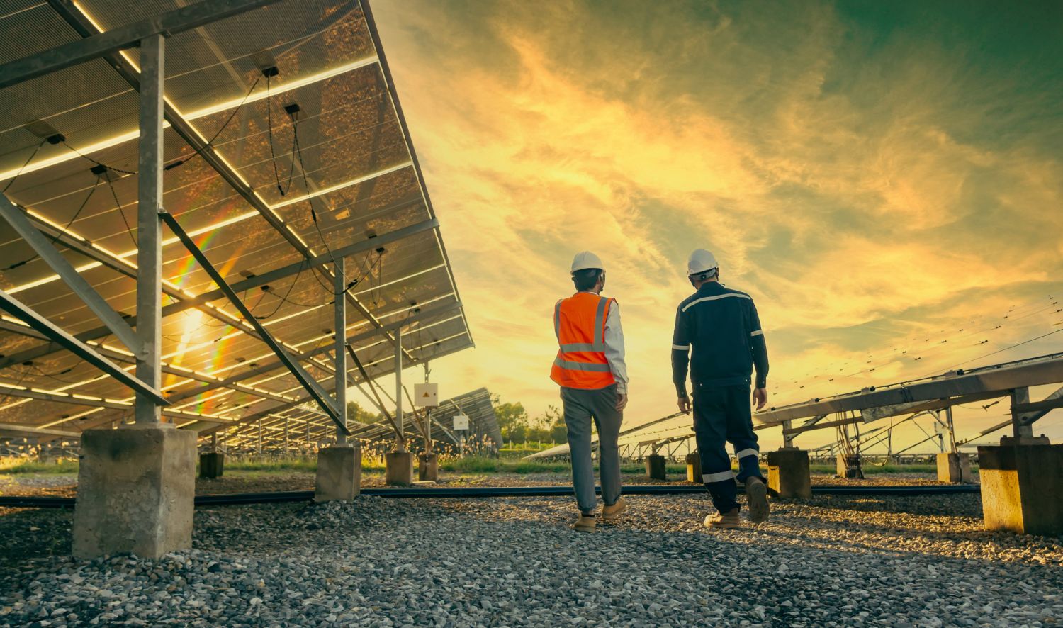 Zwei Arbeiter laufen zwischen den Platten einer Solaranlage.